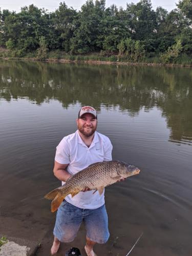 a man holding a large fish in the water at Comfort Suites Troy-I75 in Troy