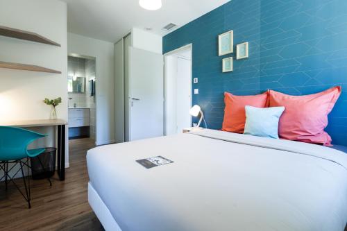 une chambre avec un lit blanc avec un mur bleu dans l'établissement La Villa Capuccine, à Nîmes