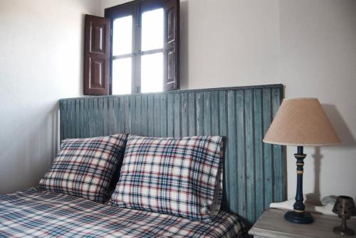 a bed with a pillow and a lamp on a table at LA MINA Alojamiento en plena naturaleza in Garganta de los Montes