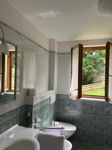 uma casa de banho com 2 lavatórios e 2 WC e uma janela em Luxury Chalet at the Foot of the Dolomites by the Castle em La Villa