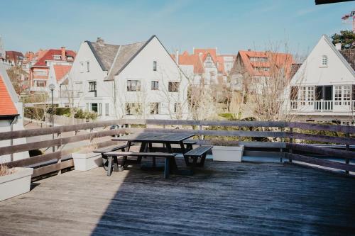 a picnic table on a wooden deck with buildings at Luxurious 4BR Villa's In Knokke in Knokke-Heist
