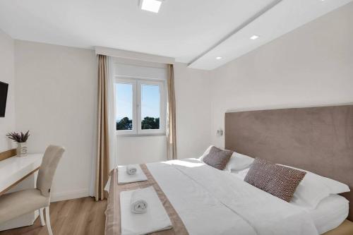 Habitación blanca con cama grande y escritorio. en Apartment Hrvoje -nur 50m bis zum Meer, en Promajna