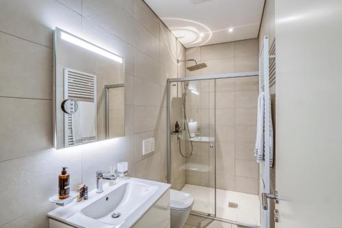 a bathroom with a sink and a shower and a toilet at Villa by @ Home Hotel Locarno in Locarno