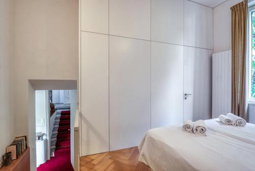 a white bedroom with two beds and a mirror at Villa by @ Home Hotel Locarno in Locarno