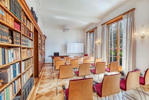 a room with rows of chairs and bookshelves at Villa by @ Home Hotel Locarno in Locarno