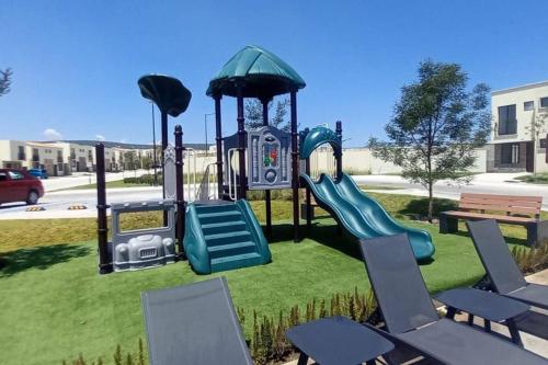 a playground with a slide and chairs on the grass at Home dream in Querétaro