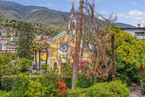 a yellow building with a clock on it in a city at Villa by @ Home Hotel Locarno in Locarno