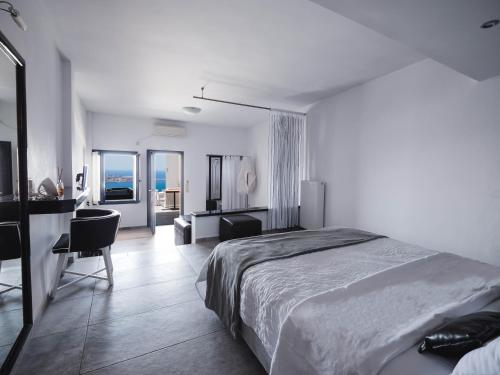 a white bedroom with a bed and a desk and a desk at Galaxy Suites & Villas in Imerovigli