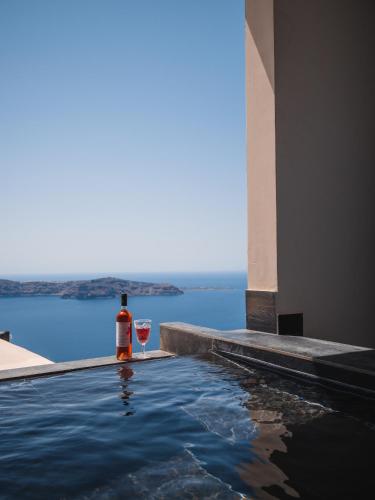 a bottle of wine and a glass sitting next to a swimming pool at Galaxy Suites & Villas in Imerovigli