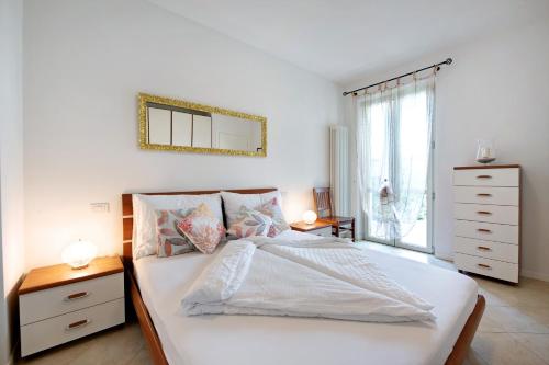 een slaapkamer met een wit bed en een spiegel aan de muur bij Katy Lake 1 in Desenzano del Garda