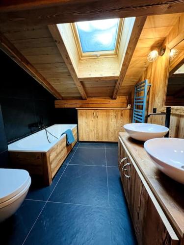 La salle de bains est pourvue de 2 lavabos, de toilettes et d'une baignoire. dans l'établissement Appartement dans chalet de luxe Megève, à Megève
