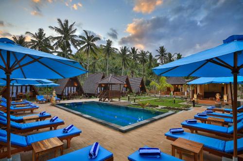 um resort com uma piscina com cadeiras azuis e guarda-sóis em Mahaloka Valley Nusa Penida em Nusa Penida