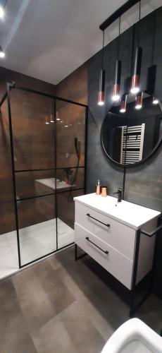 ein Badezimmer mit einem weißen Waschbecken und einem Spiegel in der Unterkunft Belweder LOFT in Nysa