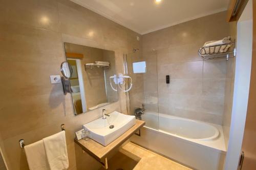 La salle de bains est pourvue d'un lavabo et d'une baignoire. dans l'établissement Hotel Mare, à Nazaré