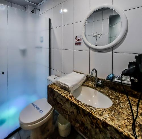 a bathroom with a sink and a toilet and a mirror at Adrenalina Motel Itaquera - Arena Corinthians in Sao Paulo