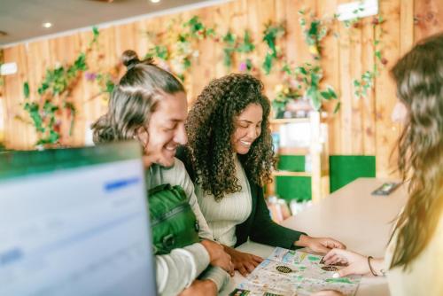 un gruppo di persone sedute attorno a un tavolo che guardano un computer di Urban Garden Hostel a Lisbona
