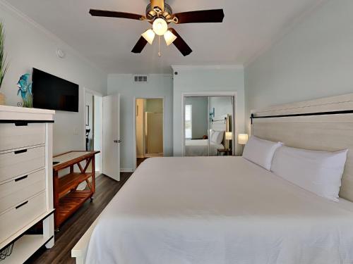1 dormitorio con cama blanca y ventilador de techo en Palm Court Yacht Club #308, en Fort Walton Beach