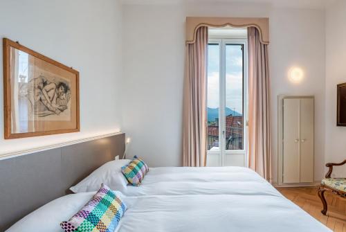 a bedroom with a white bed and a window at Villa by @ Home Hotel Locarno in Locarno