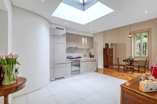a kitchen with white cabinets and a ceiling with a skylight at Villa by @ Home Hotel Locarno in Locarno