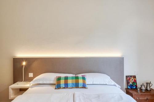 a bedroom with a large white bed with a colorful pillow at Villa by @ Home Hotel Locarno in Locarno