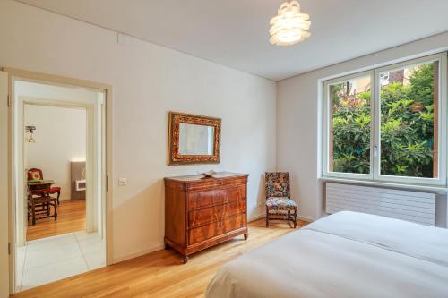 a bedroom with a bed and a dresser and a window at Villa by @ Home Hotel Locarno in Locarno
