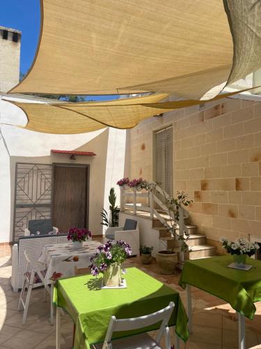 a patio with green tables and chairs and a staircase at Antico Casale Il Sambuco in Manduria