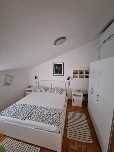 a bedroom with a large white bed and wooden floors at Home sweet home in Postira