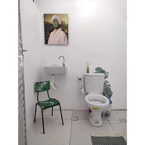 a bathroom with a toilet and a green chair at Casa Jardim Hostel BH - Santa Efigênia - Paraíso in Belo Horizonte