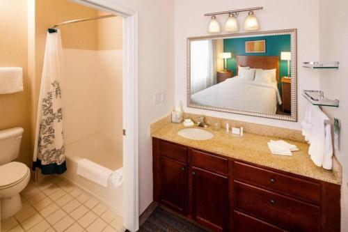 a bathroom with a sink and a bed and a mirror at Residence Inn by Marriott Wichita East At Plazzio in Wichita