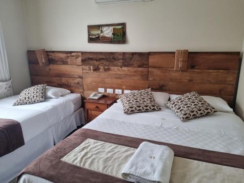 ロス・アンヘレスにあるHotel Plaza Pintoのベッド2台が備わる木製の壁の客室です。