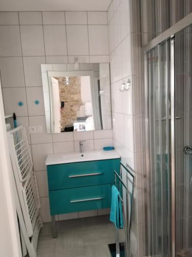 a bathroom with a blue sink and a mirror at La Flottille, La Cotinière in La Cotinière