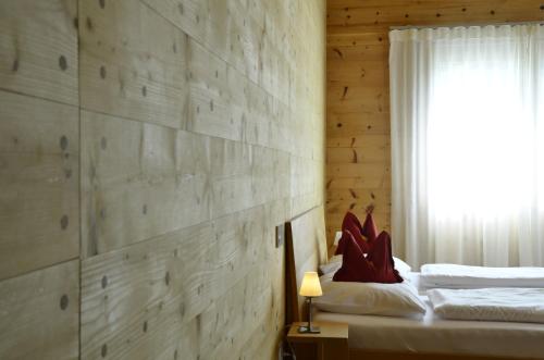 a bedroom with a wooden wall with a bed and a window at ZeiTraum Ferienwohnung Rohrhardsberg in Elzach
