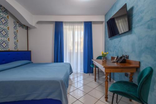 Cette chambre comprend un lit, un bureau et une télévision. dans l'établissement Hotel Ancora, à Pontecagnano