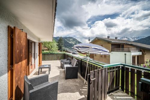 a patio with chairs and an umbrella on a balcony at Chalet Perce Neige in Châtel