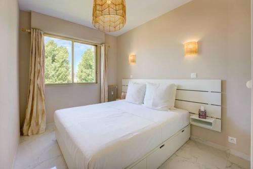 une chambre blanche avec un grand lit et une fenêtre dans l'établissement Cannes Californie Beautiful Apt with Sea View, à Cannes