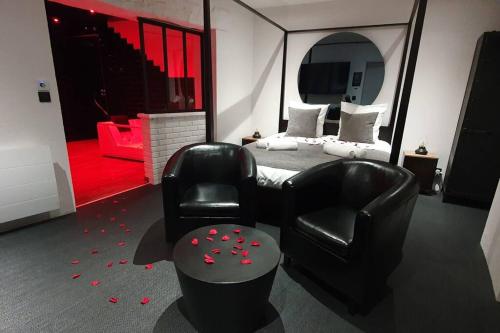 a bedroom with a bed and a black chair and a chair at Bayeuzen - Le Baldaquin - Nuitée avec Spa Privatif in Bayeux