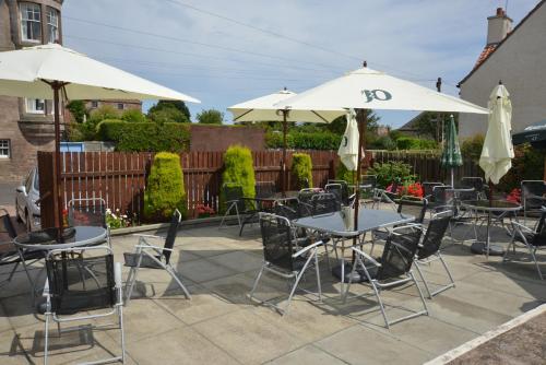 a patio with tables and chairs and umbrellas at The Golf Hotel in Crail