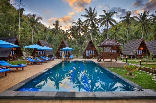 a resort with a pool and chairs and palm trees at Mahaloka Valley Nusa Penida in Nusa Penida