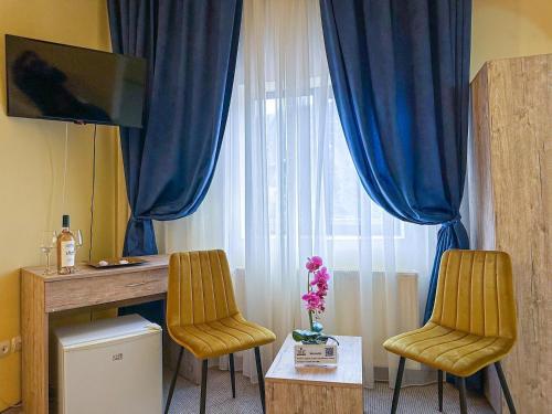 dwa krzesła i stół w pokoju z oknem w obiekcie Hotel Pin Azuga w mieście Azuga