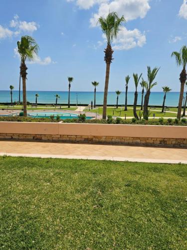 a park with palm trees and the ocean in the background at marina beach appartement in M'diq