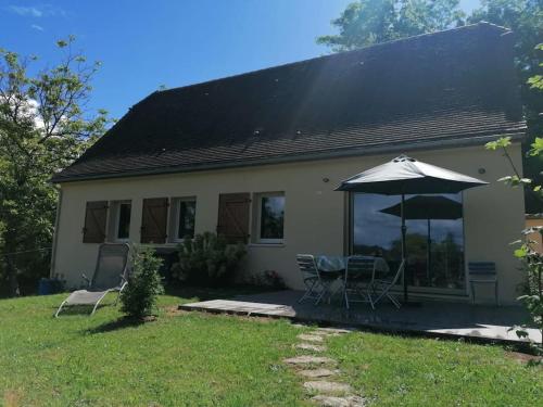 a house with an umbrella and a table and chairs at Magnifique maison avec vue panoramique in Carlux
