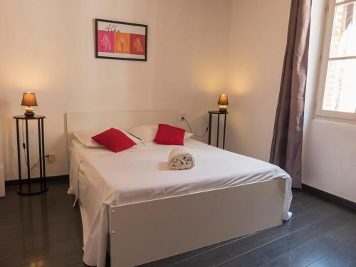1 dormitorio con 1 cama blanca y 2 almohadas rojas en Le Castelviel, en Albi