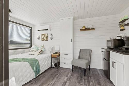 a white bedroom with a bed and a chair at New Wilderness Hideout-Cozy Container Home in Fredericksburg