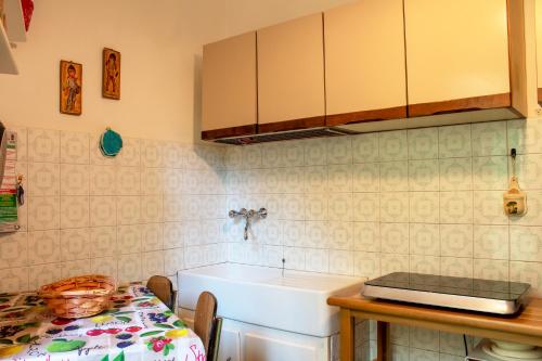 uma cozinha com um lavatório e uma mesa com uma mesa de sidx em [300 metri dal mare] Relax con aria condizionata em Spotorno