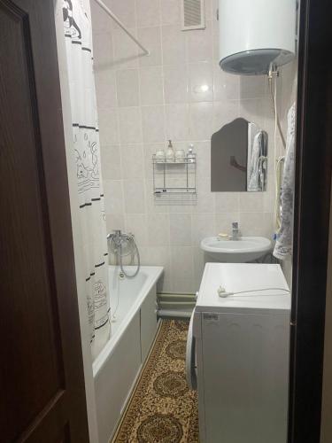 a bathroom with a tub and a toilet and a sink at Уютная 2-х комнатная квартира in Qyzylorda