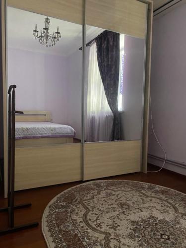 1 dormitorio con puerta de cristal, cama y espejo en Уютная 2-х комнатная квартира en Kyzylorda