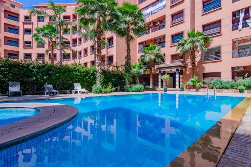 - une piscine en face d'un bâtiment avec des palmiers dans l'établissement Caprice palace hivernage, à Marrakech