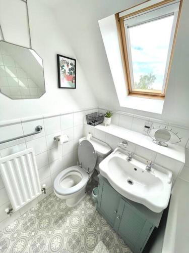 a bathroom with a toilet and a sink and a window at Luxurious 2 bed in Beaulieu Park in Broomfield