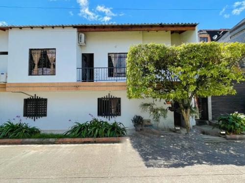 Una casa blanca con un árbol delante. en Apartamento de Descanso - Doradal, en Doradal