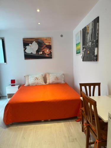 - une chambre avec un lit orange et une table dans l'établissement STUDETTE Beausejour, à Cannes